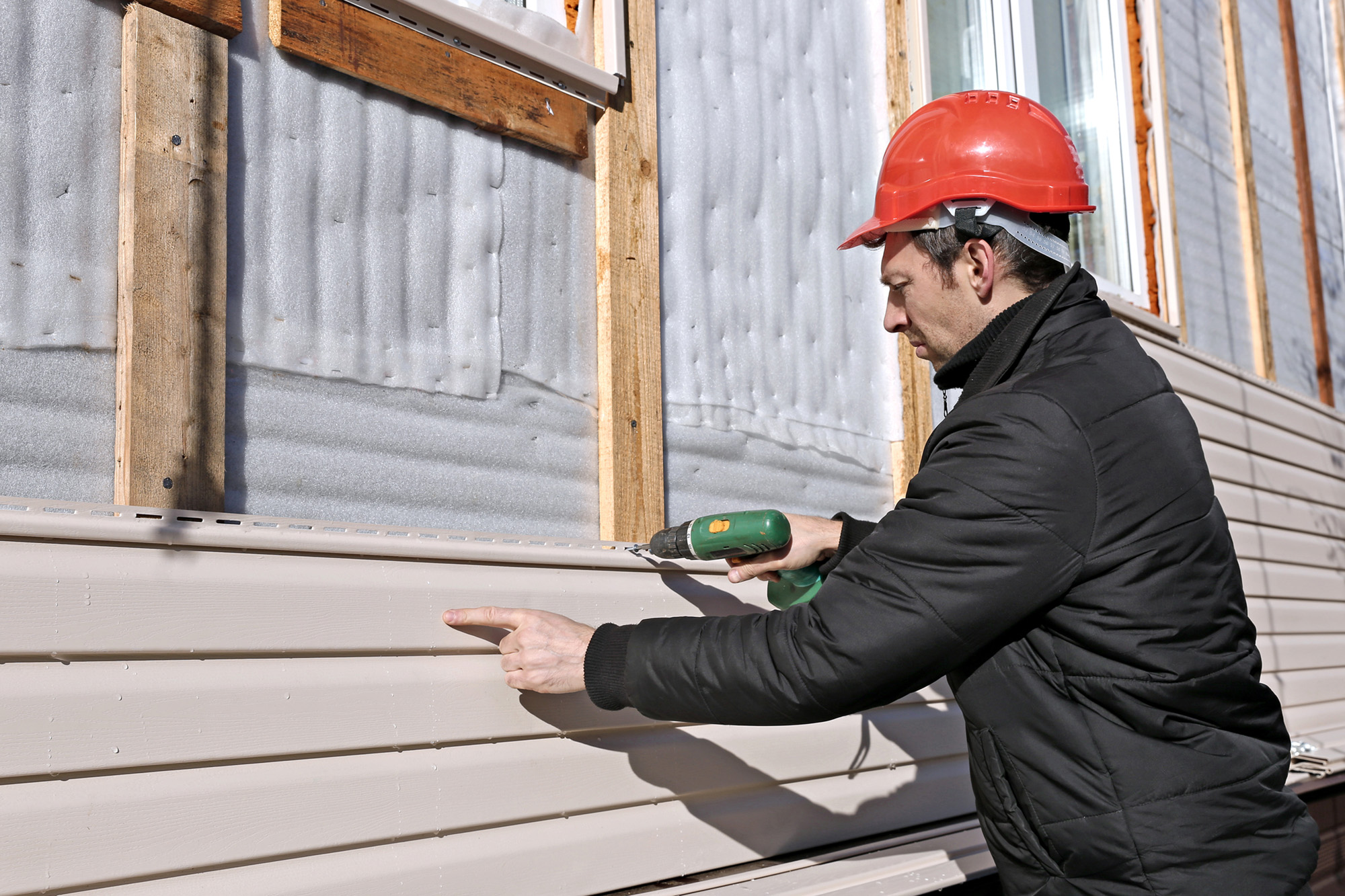 A Worker Installs Panels Beige Siding On The Facade Of The House